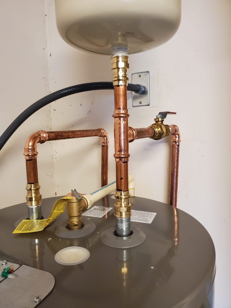 The image shows plumbing connections on a water heater, including copper pipes and valves.